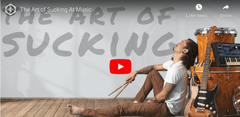 A guitar player sitting againt a speaker